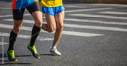 Marathon running race, two men runners on city roads, detail on legs,