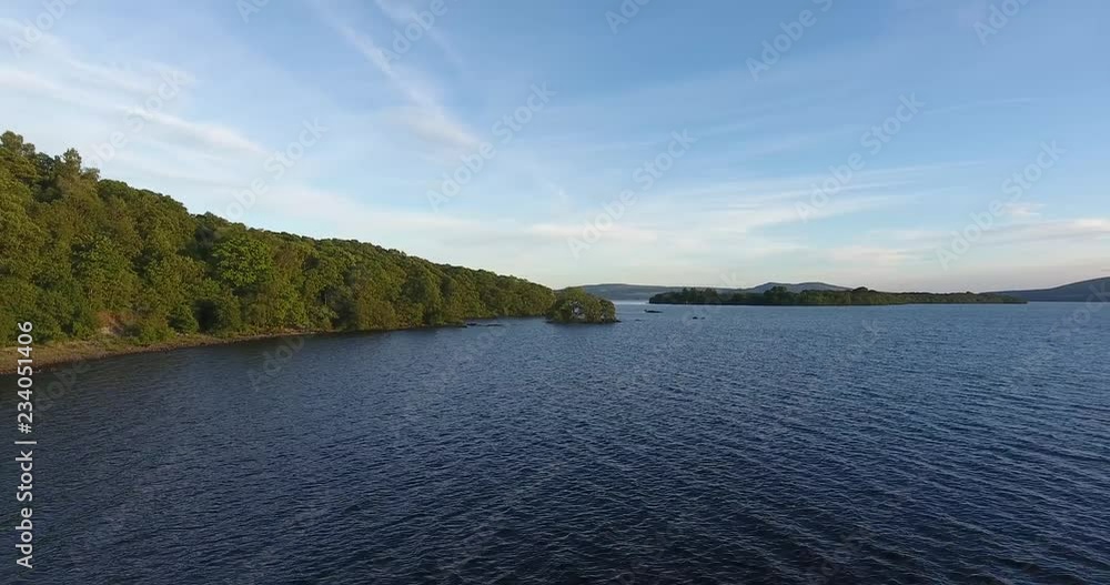 Scottish Loch Featuring a Distant Landscape with Green Hills - Loch Lomond inside The Trossachs National Park Scottish Loch Featuring a Distant Landscape with Green Hills - Loch Lomond inside The Trossachs National Park