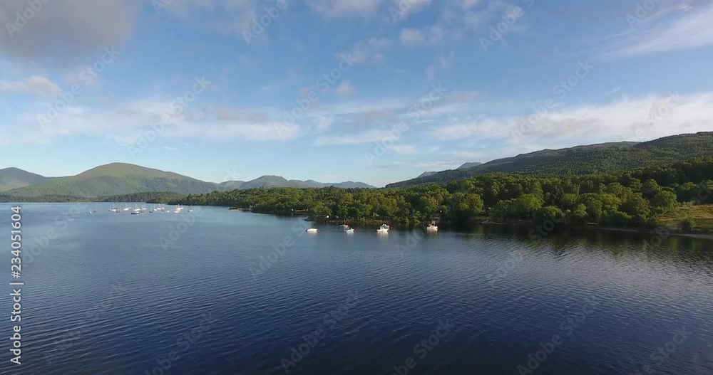 Scottish Loch Featuring a Distant Landscape with Green Hills - Loch Lomond inside The Trossachs National Park Scottish Loch Featuring a Distant Landscape with Green Hills - Loch Lomond inside The Trossachs National Park