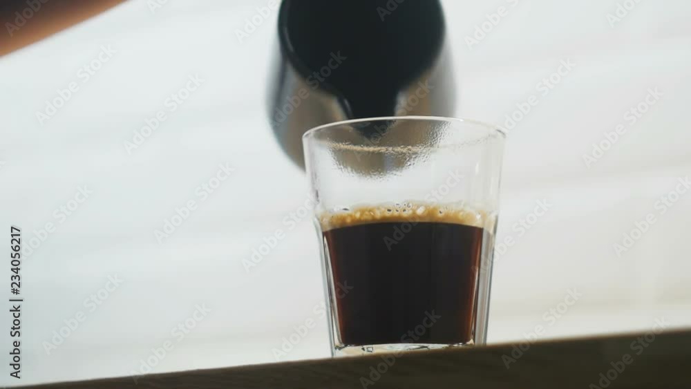 Pouring milk into a cup of coffee.
