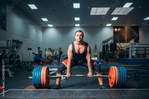 Male weightlifter prepares to pull heavy barbell