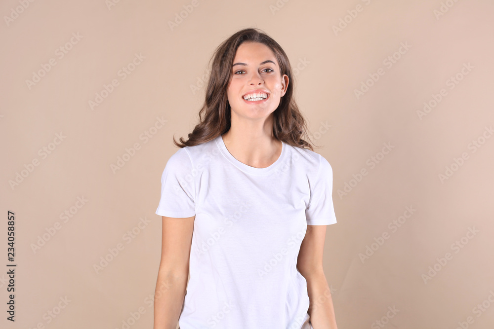 Cheerful brunette woman dressed in basic clothing looking at camera, isolated on beige background. Cheerful brunette woman dressed in basic clothing looking at camera, isolated on beige background.