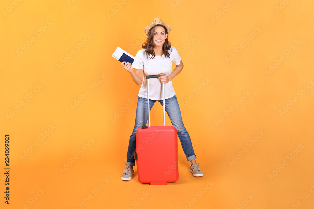 Young tourist girl in summer casual clothes, with red suitcase, passport, tickets isolated on beige background. Young tourist girl in summer casual clothes, with red suitcase, passport, tickets isolated on beige background.