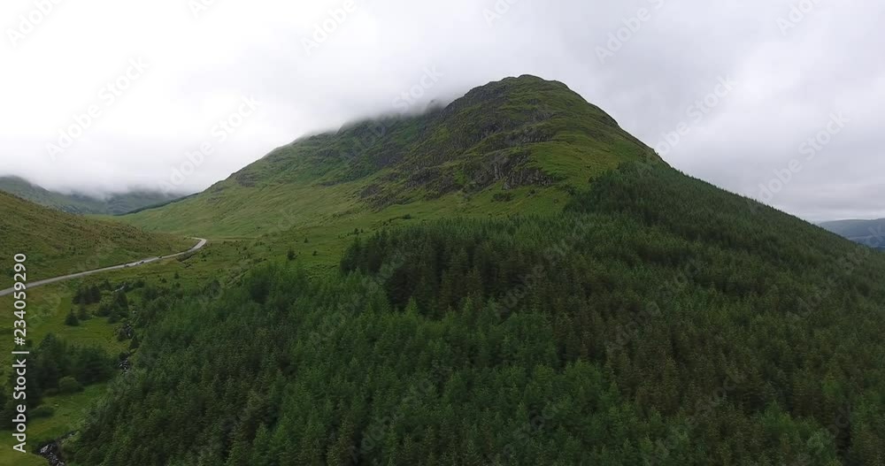 Small Road and River Drone Shot Between Hills in Scotland - Near Glencoe in the Highlands Small Road and River Drone Shot Between Hills in Scotland - Near Glencoe in the Highlands