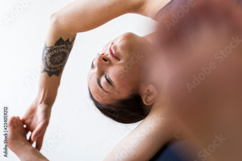 Young tattooed woman doing a Head-of-Knee Pose or Janu Sirsasana