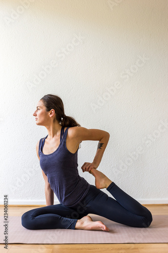 dark-haired European woman in her 30’s practices yoga at home