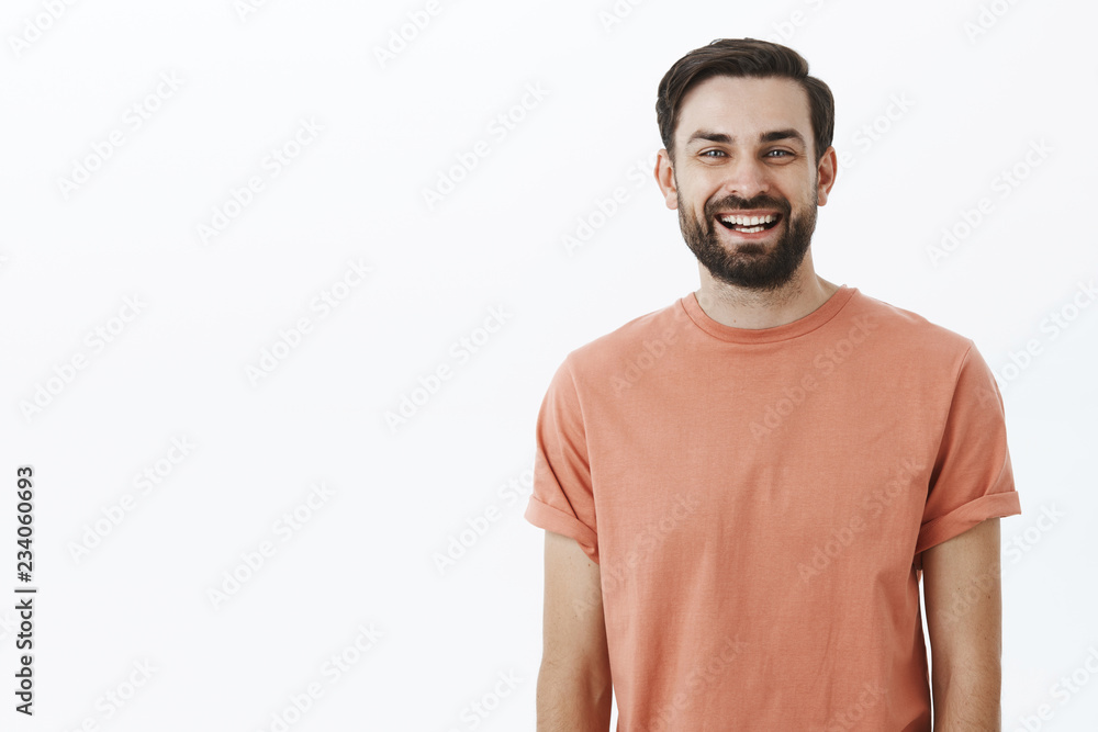 Waist-up shot of bright and cheerful emotive friendly bearded 30s man with broad smile gazing satisfied and upbeat at camera as posing in pink t-shirt over gray background, amused and enthusiastic Waist-up shot of bright and cheerful emotive friendly bearded 30s man with broad smile gazing satisfied and upbeat at camera as posing in pink t-shirt over gray background, amused and enthusiastic