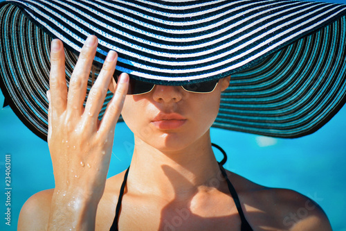 Portrait of a girl in glasses and a hat on a tropical beach