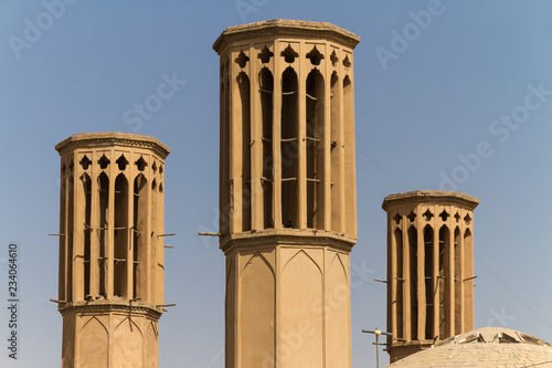 Iconic Badgirs (windtowers) in the mud-brick desert city of Yazd, Iran. An ancient rooftop air conditioning system that captures the wind for cooling the houses below. photo