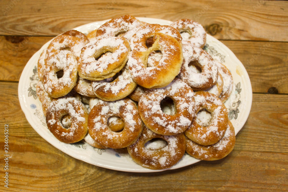 Sweet, flavorful donuts in powder in a plate on a wooden table Sweet, flavorful donuts in powder in a plate on a wooden table