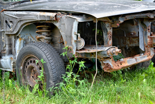 Old rusty car. Beautiful photo of a bumper of an old rusty vehicle with green grass background. Broken and forgotten. An old discarded rusted out scrap car that has been abandoned on a farm.