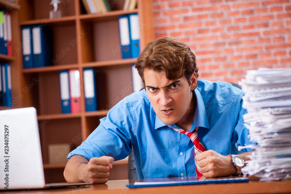 Young employee with excessive work sitting at the office Young employee with excessive work sitting at the office
