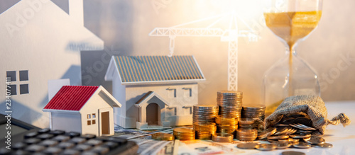 Real estate or property development. Construction business investment concept. Home mortgage loan rate. Coin stack on international banknotes with calculator, house and crane models on the table. photo