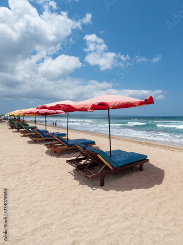 White sand and blue ocean. Various colorful beach umbrellas and pillows in Kuta, Bali. October, 2018