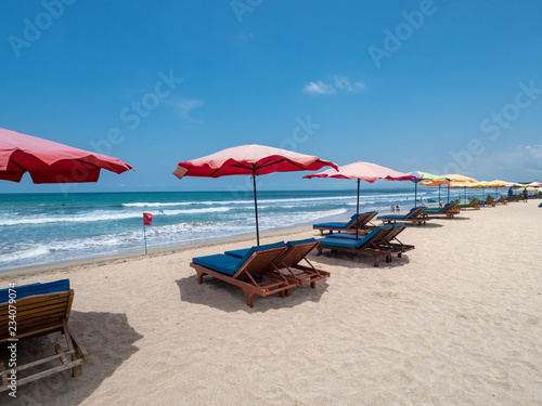 White sand and blue ocean. Various colorful beach umbrellas and pillows in Kuta, Bali. October, 2018