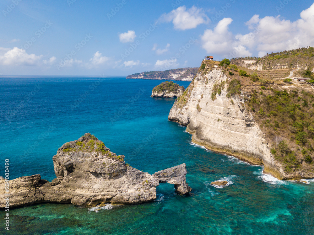 Aerial view to beautiful arched rock in ocean on Atuh beach. Photo from drone. Nusa Penida, Bali, Indonesia