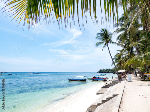 Amazing tropical beach background from Alona Beach at Panglao Bohol island with Beach chairs on the white sand beach with cloudy blue sky and palm trees. Philippines, november, 2018