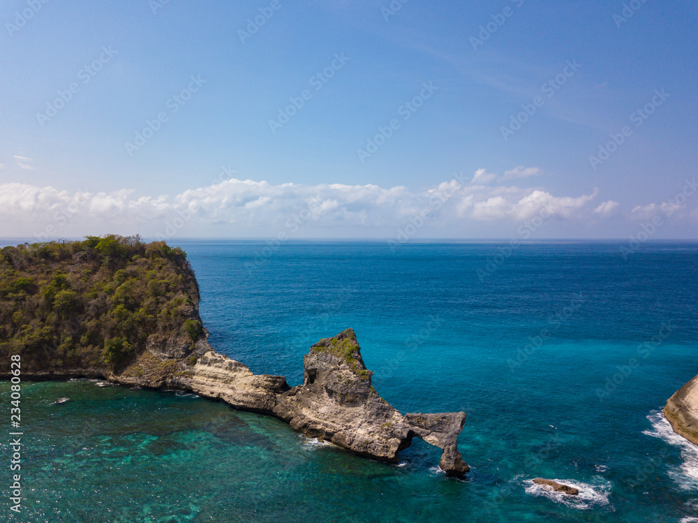 Aerial view to beautiful arched rock in ocean on Atuh beach. Photo from drone. Nusa Penida, Bali, Indonesia