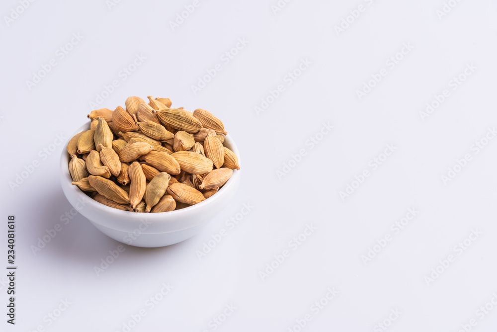 Dry Cardamom pod in a stone mortar, isolated on white background, latin term Elettaria cardamomum, with copy space, angle view, soft light. Dry Cardamom pod in a stone mortar, isolated on white background, latin term Elettaria cardamomum, with copy space, angle view, soft light.