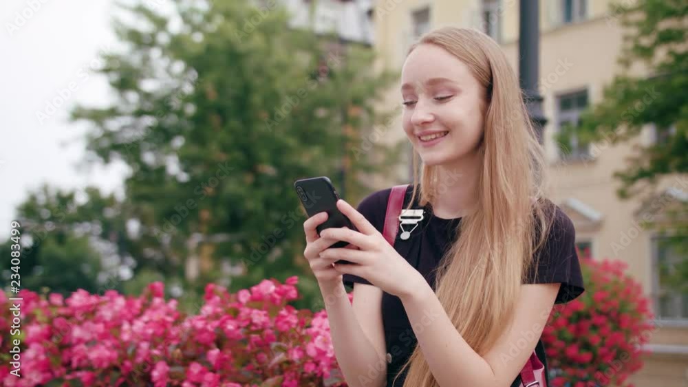 An attractive young red-haired lady and using a phone in town. Close-up dolly shot. Soft focus An attractive young red-haired lady and using a phone in town. Close-up dolly shot. Soft focus
