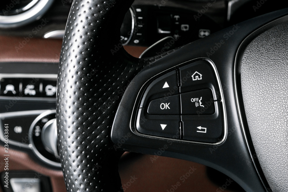 Media and navigation control buttons on a steering wheel of a Modern car. Car interior details. Brown leather interior of the luxury modern car. Modern car interior. Car detailing