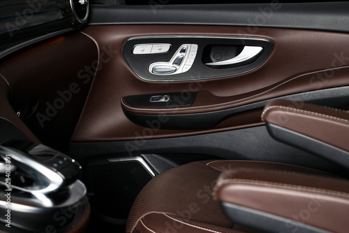 Door handle with Power seat control buttons of a luxury passenger car. Brown leather interior with white stitching of the luxury modern car. Modern car interior details. Car detailing