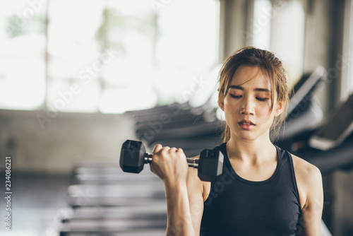 Fitness woman in training exercises with dumbbells.