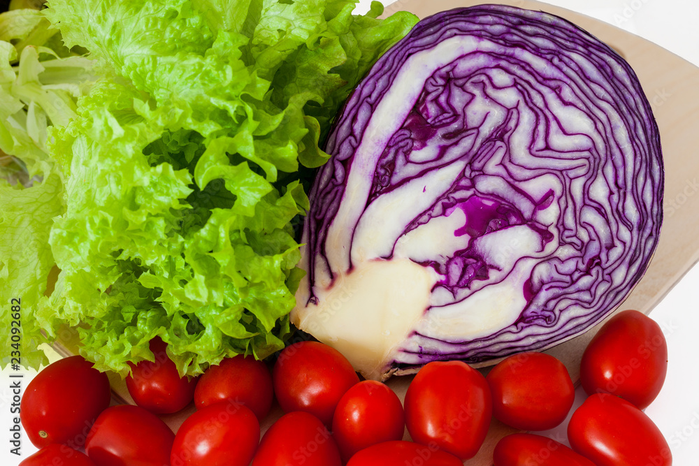 Obraz premium Half a head of red cabbage, green salad and tomatoes. Isolated.