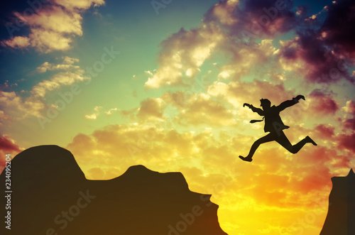 Businessman jumps over rocky mountain. Business and success concept