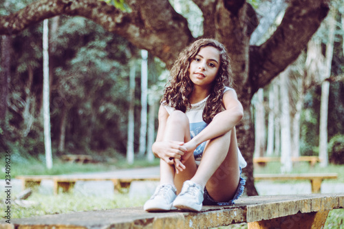 Beautiful smiling girl sitting on the bench in the park