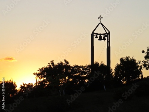 Beautiful Colorful Sunset Over Silhouette of Bell Tower with Cross and Four Bells