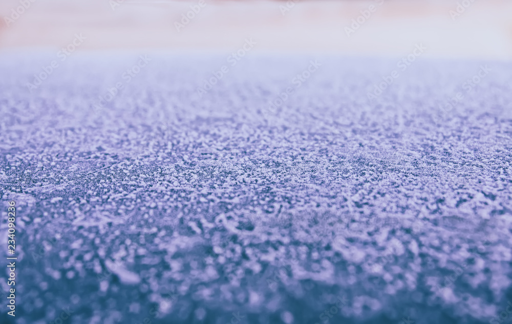 Background: smooth metallic surface covered with thick frost and illuminated by dim morning light