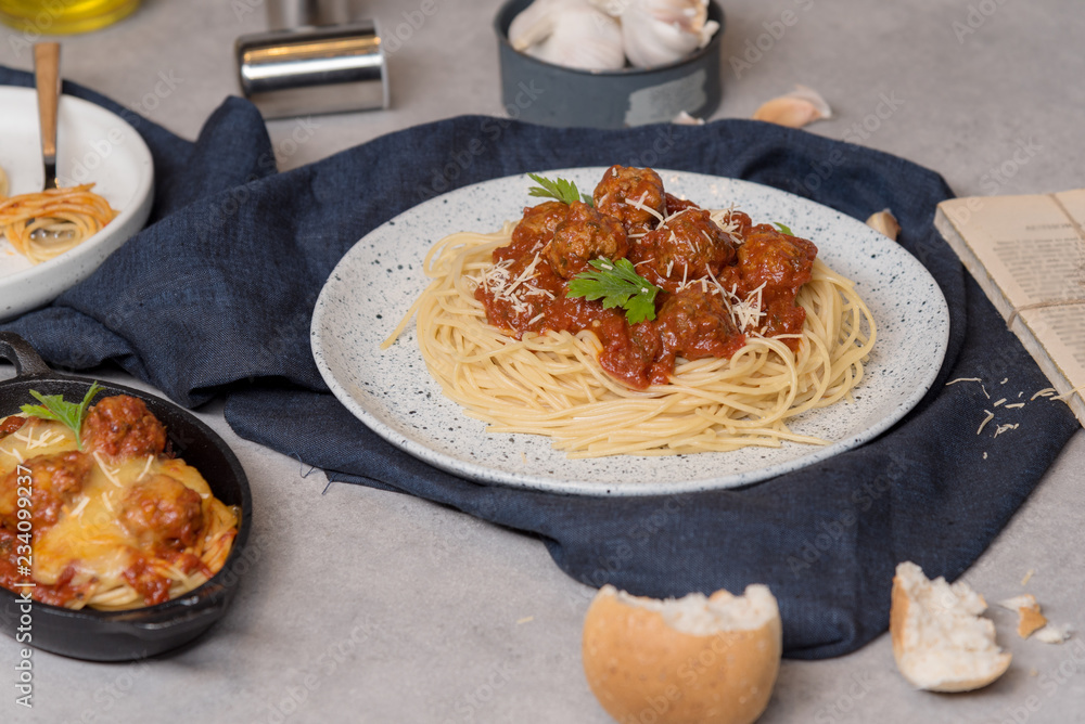 Fototapeta premium Homemade spaghetti or pasta with meatball and cheese in tomato sauce placed in a white dish. On dark blue tablecloth on the table with Bread Pie.