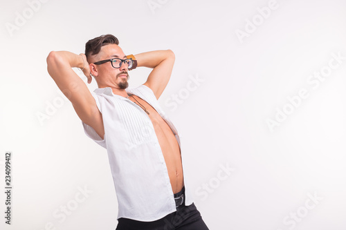 People, clothing and style concept - young sexy handsome man posing in white shirt on white background with copy space