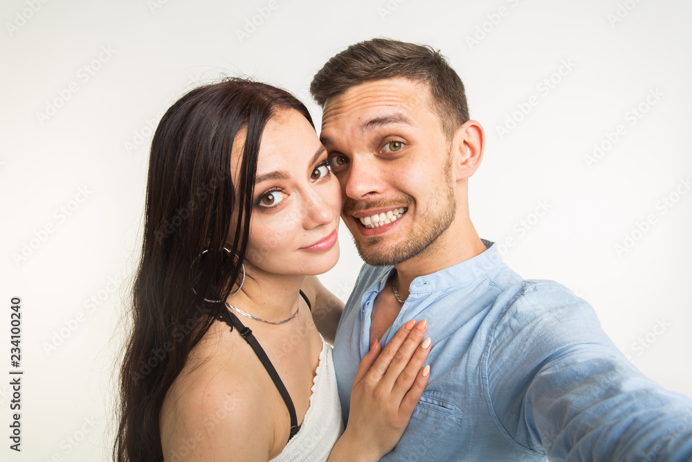 Relationship and people concept- man taking selfie with his wonderful woman on mobile phone over white background