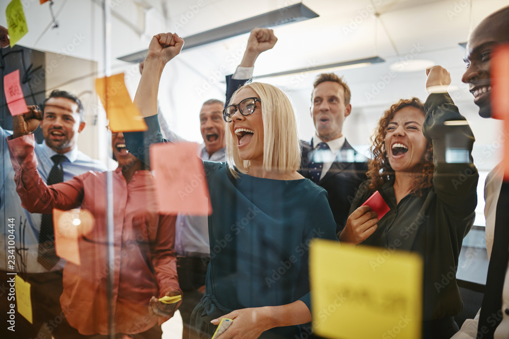 Businesspeople cheering while brainstorming with sticky notes in - obrazy, fototapety, plakaty 
