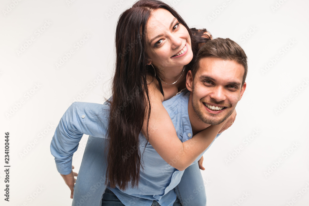 Emotional, love and people concept - young woman climbed the guy on the back and they happy and smile Emotional, love and people concept - young woman climbed the guy on the back and they happy and smile