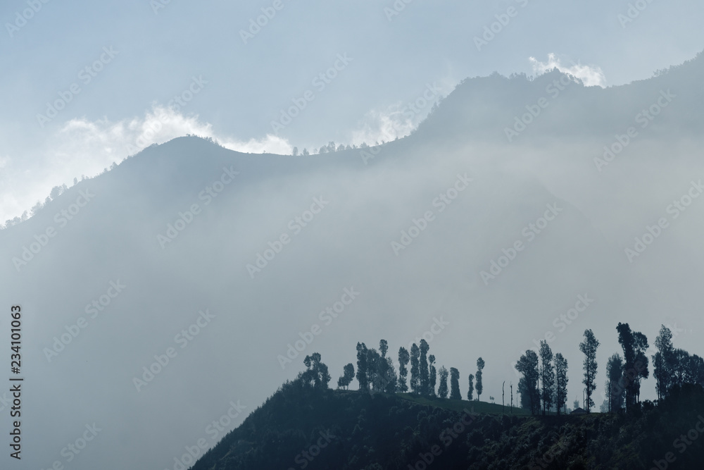 In the first morning light view on a mountain chain surrounded by clouds and fog - Location: Indonesia, Java, Mt. Bromo