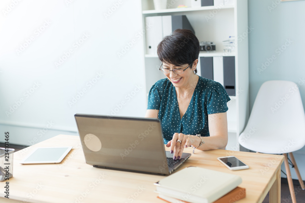 Business people and technology concept - Middle age woman is working at the office with laptop Business people and technology concept - Middle age woman is working at the office with laptop