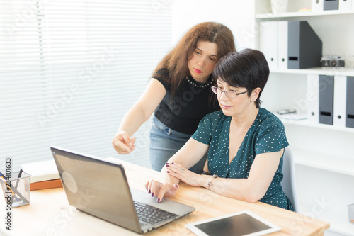 People, technology and communication concept - middle-aged woman and young woman are working together
