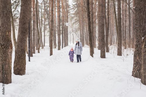 Happy family mother and child daughter having fun, playing at winter walk outdoors © satura_