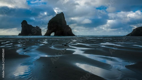 Timelapse of beautiful beach with spectacular rocks arch on the coast of New Zealand. Wharariki beach.
