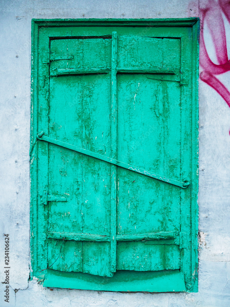 Old green closed window with shutters. Ruined wall of an old house Old green closed window with shutters. Ruined wall of an old house