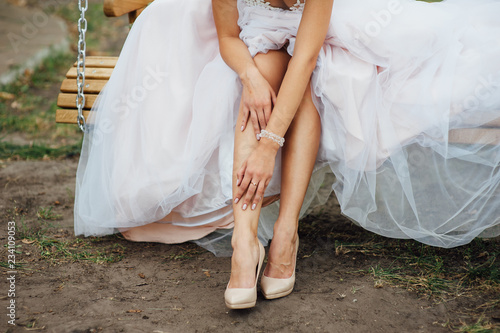Detail of bridal legs with shoes sitting on the wooden table