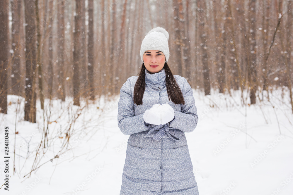 Obraz premium Christmas, holidays and season concept - Young beautiful smiling woman holding snow in hands in winter outdoors