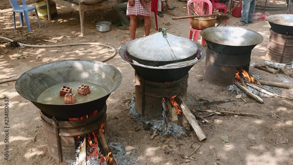 Wok cooking on large charcoal and wood brazier stoves lined up outdoors Wok cooking on large charcoal and wood brazier stoves lined up outdoors
