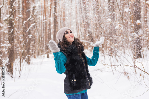 Happy young woman plays with a snow at snowy forest outdoor