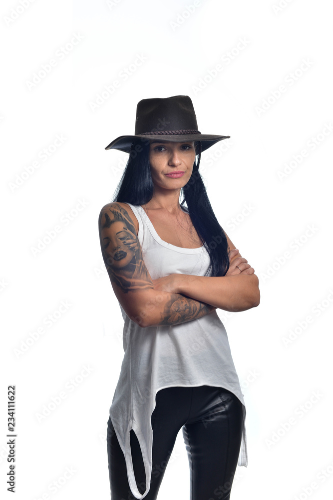 Dark long haired girl wearing a cowboy hat and a sleeveless white shirt posing isolated on white. Dark long haired girl wearing a cowboy hat and a sleeveless white shirt posing isolated on white.