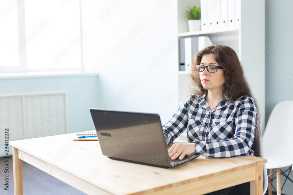 Technology, business and people concept - Serious woman in glasses working at the computer in office Technology, business and people concept - Serious woman in glasses working at the computer in office