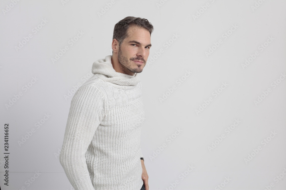 Man with a white sweater and blue jeans standing in front of a white background Man with a white sweater and blue jeans standing in front of a white background